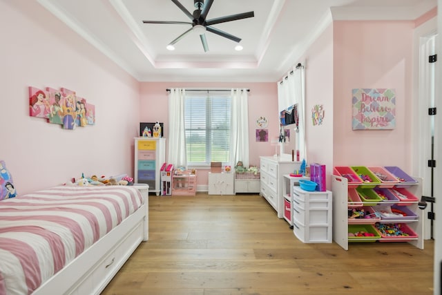 bedroom featuring ornamental molding, light hardwood / wood-style floors, ceiling fan, and a tray ceiling