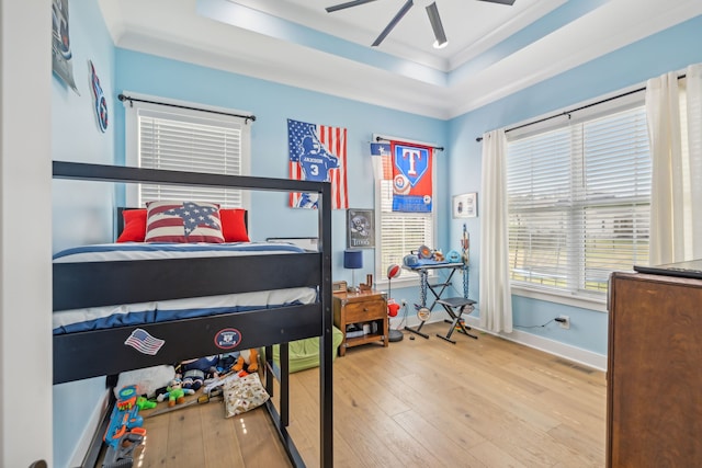 bedroom featuring a tray ceiling, light hardwood / wood-style floors, ceiling fan, and crown molding