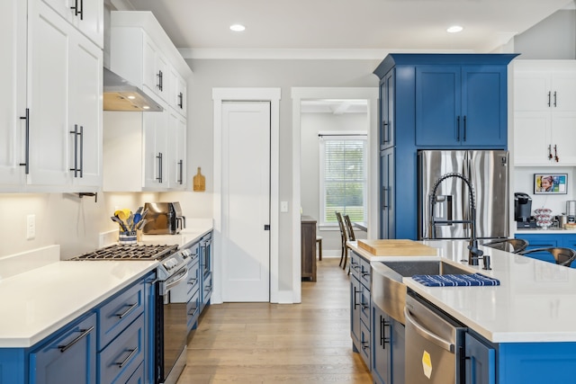 kitchen with stainless steel appliances, blue cabinetry, light hardwood / wood-style flooring, crown molding, and white cabinets