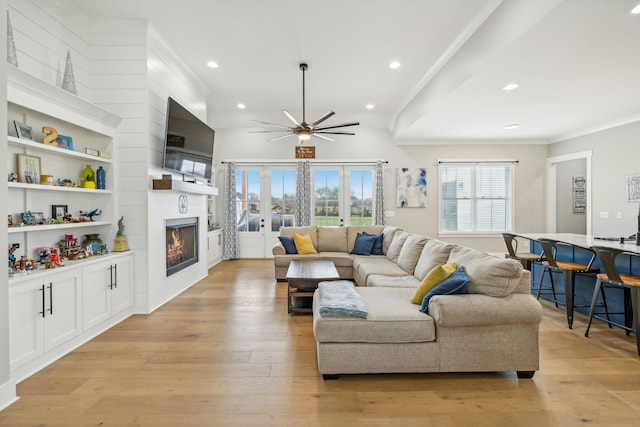 living room with ornamental molding, ceiling fan, light hardwood / wood-style floors, and a fireplace