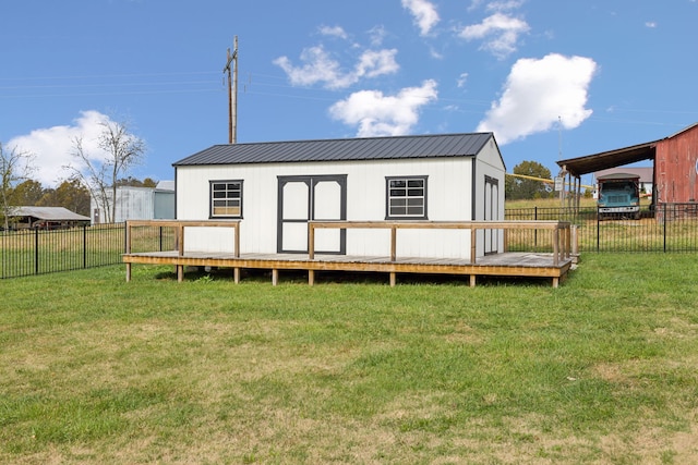 rear view of house featuring an outbuilding, a lawn, and a wooden deck