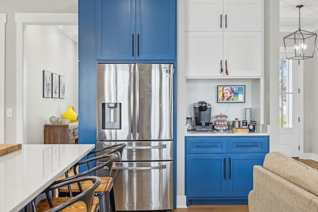 kitchen with hardwood / wood-style flooring, stainless steel fridge with ice dispenser, pendant lighting, and blue cabinets