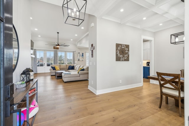 living room featuring beamed ceiling, light hardwood / wood-style floors, and ceiling fan with notable chandelier