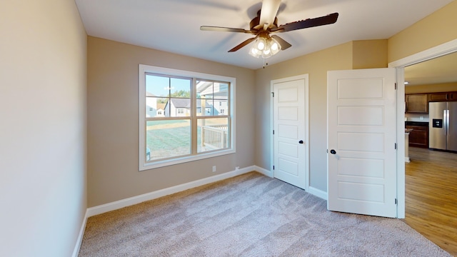 unfurnished bedroom with stainless steel refrigerator with ice dispenser, ceiling fan, and light hardwood / wood-style floors