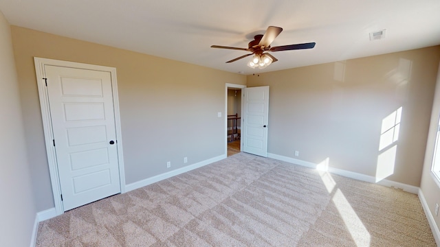 spare room with ceiling fan and light carpet