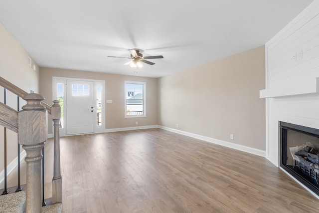 foyer with ceiling fan, wood-type flooring, and a large fireplace