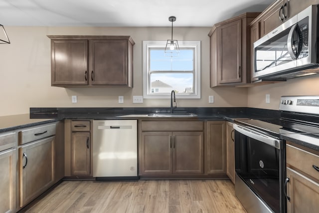 kitchen featuring light hardwood / wood-style floors, appliances with stainless steel finishes, hanging light fixtures, and sink