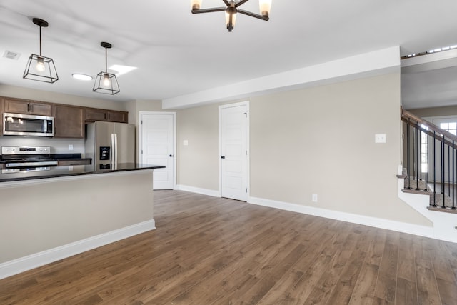 kitchen featuring dark hardwood / wood-style flooring, appliances with stainless steel finishes, dark brown cabinets, and hanging light fixtures