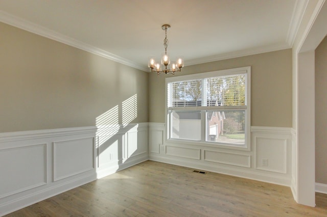 unfurnished dining area featuring light hardwood / wood-style flooring, crown molding, and a notable chandelier