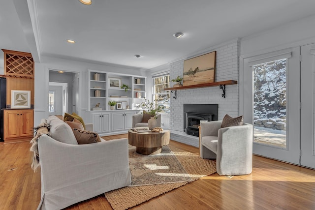 living room with light hardwood / wood-style flooring, a brick fireplace, and crown molding