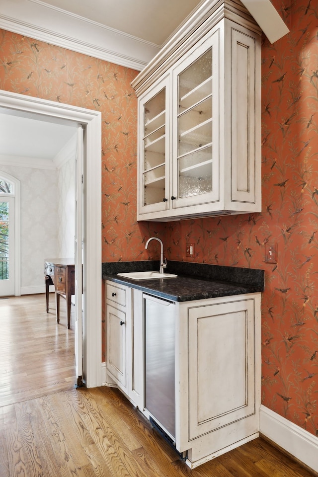 bar featuring light wood-type flooring, sink, and crown molding