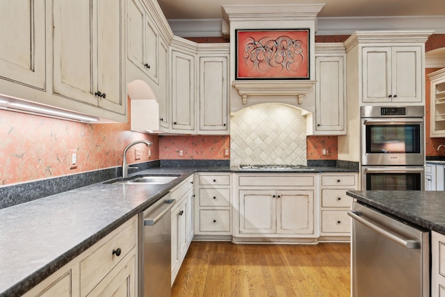 kitchen featuring sink, appliances with stainless steel finishes, cream cabinetry, and light wood-type flooring