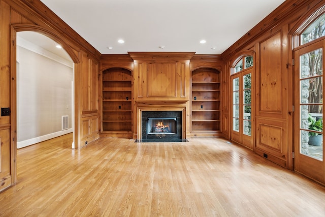 unfurnished living room with crown molding, light hardwood / wood-style flooring, and built in shelves