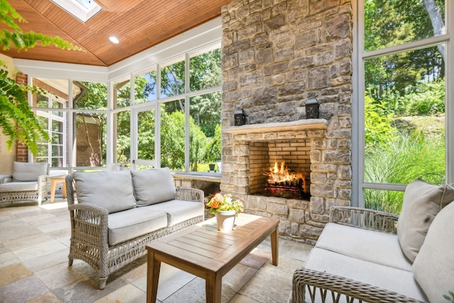 sunroom featuring a fireplace, wood ceiling, and lofted ceiling with skylight