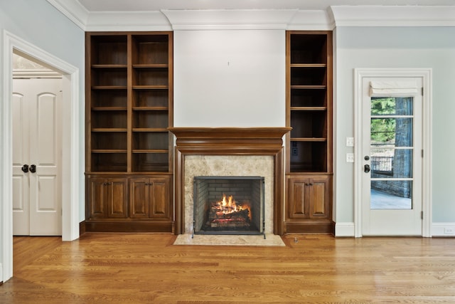 unfurnished living room featuring crown molding, a premium fireplace, and light wood-type flooring