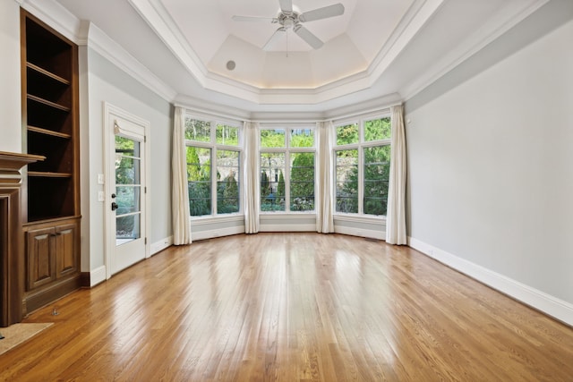 empty room with light hardwood / wood-style floors, crown molding, a raised ceiling, and ceiling fan