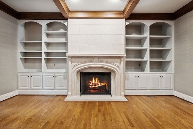 unfurnished living room featuring beam ceiling, a tile fireplace, and light hardwood / wood-style floors