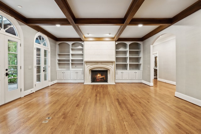 unfurnished living room featuring beam ceiling, french doors, light wood-type flooring, and coffered ceiling