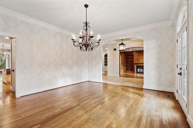 interior space featuring hardwood / wood-style floors, ornamental molding, and a chandelier