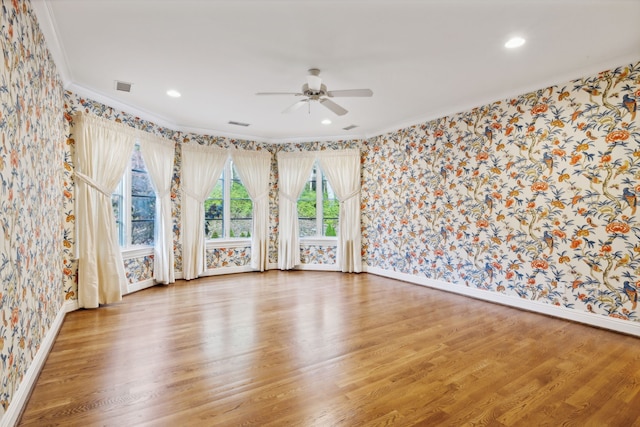 empty room featuring ceiling fan, crown molding, and wood-type flooring