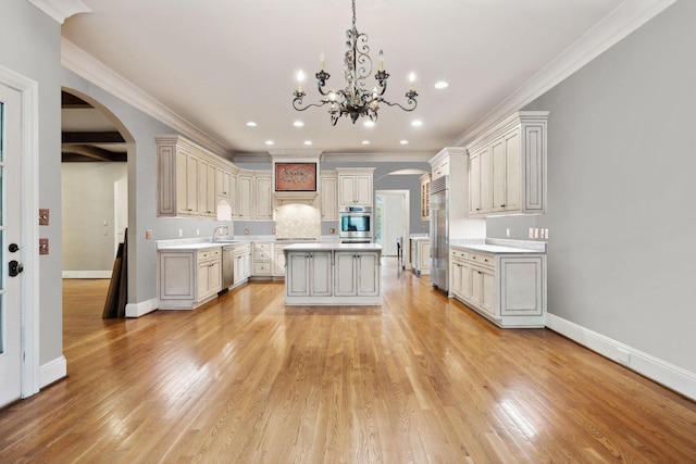 kitchen with hanging light fixtures, appliances with stainless steel finishes, a center island, and crown molding