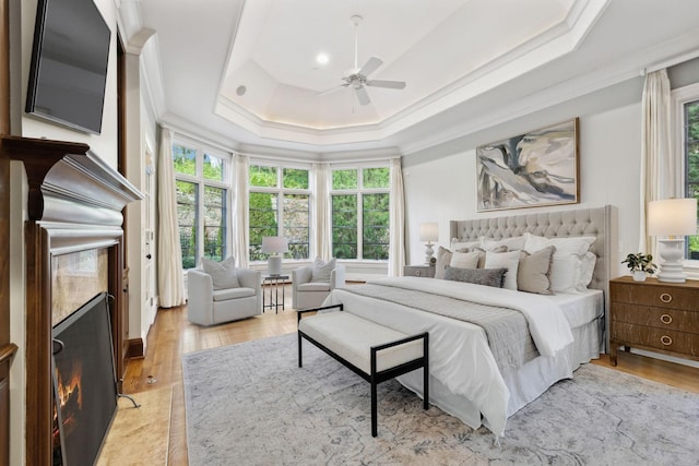 bedroom featuring ceiling fan, crown molding, light hardwood / wood-style floors, and a raised ceiling