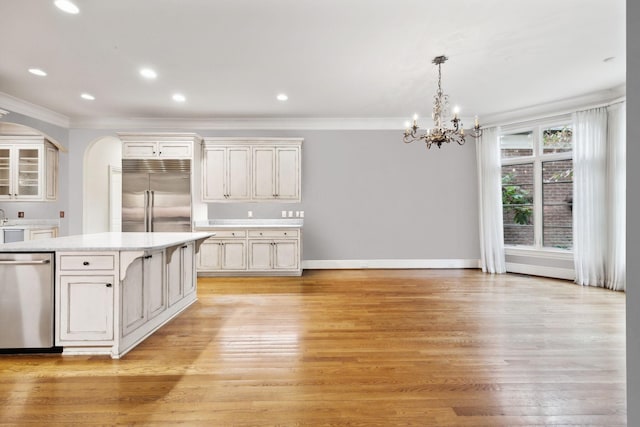 kitchen featuring light hardwood / wood-style floors, appliances with stainless steel finishes, pendant lighting, a kitchen island, and crown molding