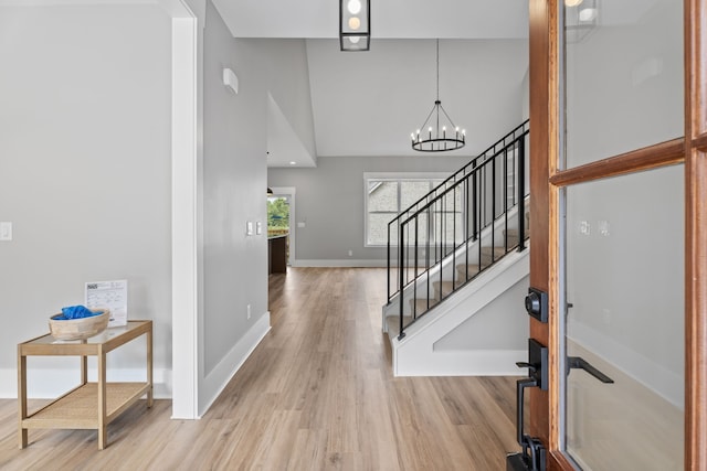 entrance foyer featuring high vaulted ceiling, light hardwood / wood-style floors, and a notable chandelier