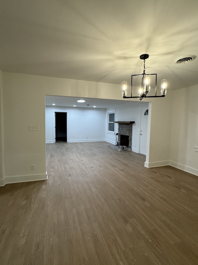 unfurnished living room featuring a stone fireplace and dark wood-type flooring