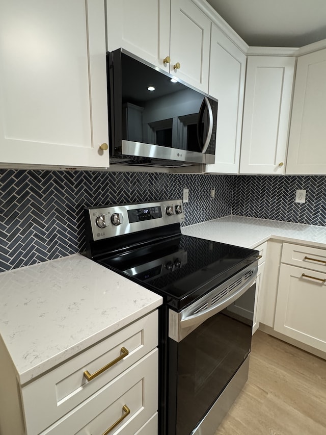 kitchen featuring light hardwood / wood-style flooring, tasteful backsplash, white cabinetry, and stainless steel appliances