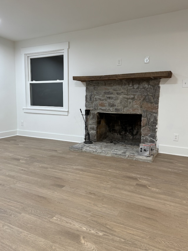 unfurnished living room with a stone fireplace and hardwood / wood-style floors