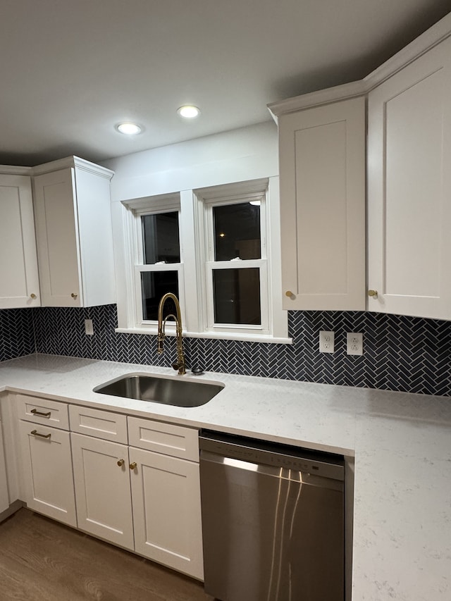 kitchen with dark wood-type flooring, white cabinets, sink, stainless steel dishwasher, and light stone countertops