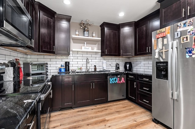 kitchen with dark stone counters, light wood-type flooring, sink, and stainless steel appliances