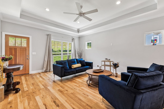 living room featuring light hardwood / wood-style flooring, crown molding, and a tray ceiling