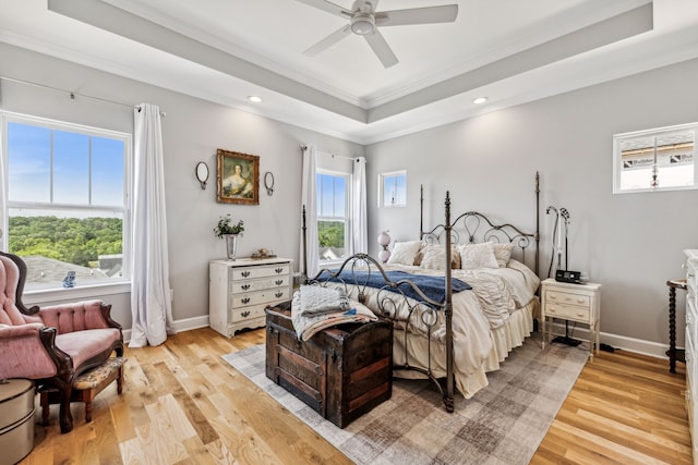 bedroom featuring ceiling fan, a raised ceiling, light hardwood / wood-style flooring, and ornamental molding