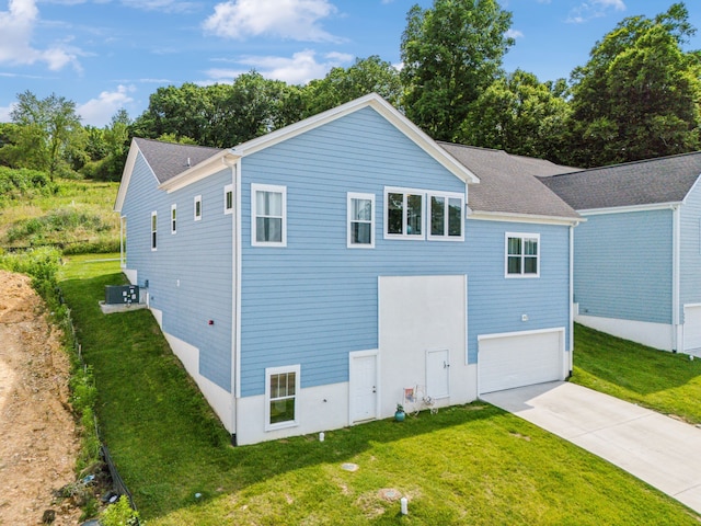 exterior space with a garage, a lawn, and cooling unit