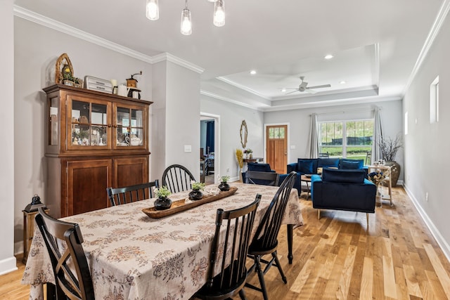 dining area featuring ceiling fan, light hardwood / wood-style flooring, crown molding, and a tray ceiling