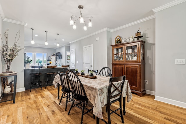 dining room with a notable chandelier, ornamental molding, and light hardwood / wood-style flooring