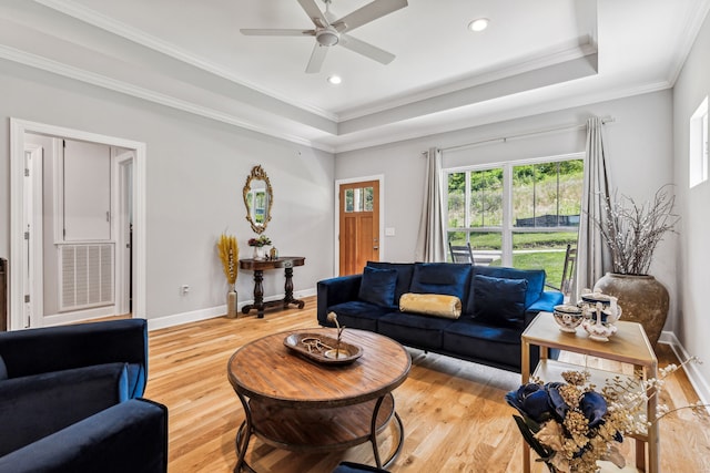 living room featuring a tray ceiling, hardwood / wood-style floors, ceiling fan, and crown molding