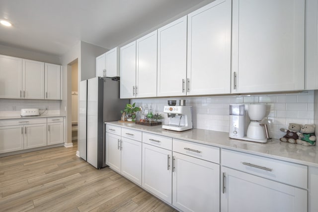 kitchen featuring white cabinetry, light wood-type flooring, and tasteful backsplash