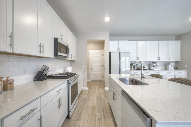 kitchen with light hardwood / wood-style flooring, white cabinets, sink, and stainless steel appliances