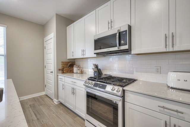 kitchen featuring light stone counters, backsplash, white cabinetry, appliances with stainless steel finishes, and light wood-type flooring