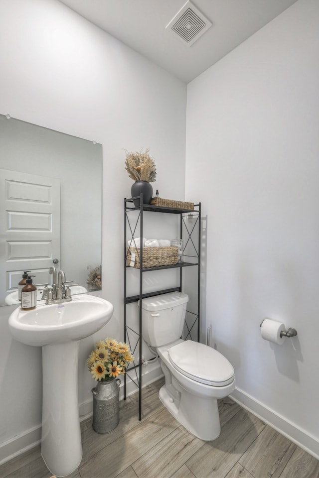 bathroom with wood-type flooring, toilet, and sink