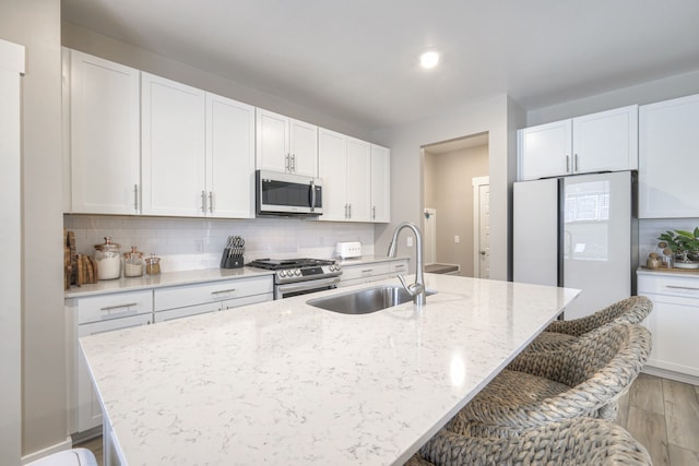 kitchen featuring appliances with stainless steel finishes, sink, a center island with sink, and white cabinets