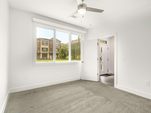 carpeted empty room featuring baseboards and a ceiling fan