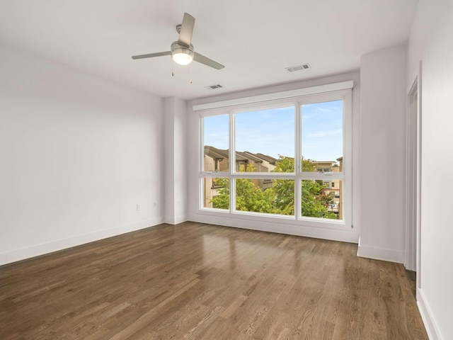 empty room featuring wood finished floors, baseboards, and a ceiling fan