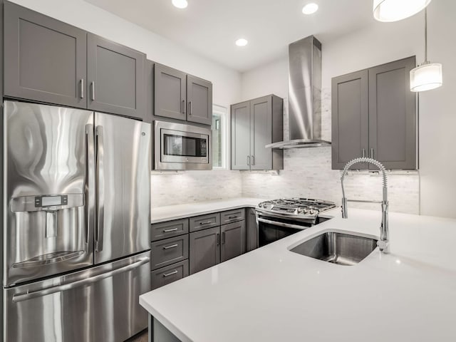 kitchen featuring stainless steel appliances, tasteful backsplash, wall chimney exhaust hood, gray cabinets, and pendant lighting