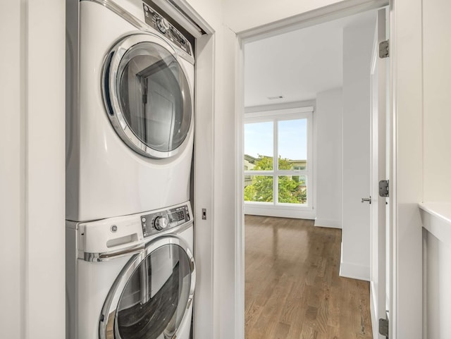 clothes washing area with hardwood / wood-style floors and stacked washer / dryer