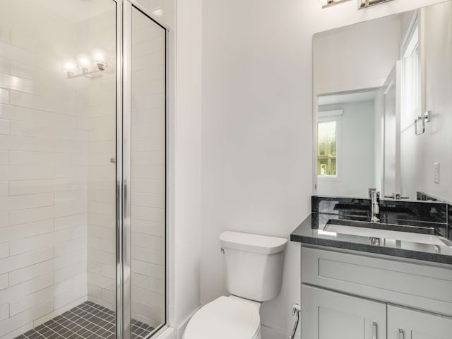 bathroom featuring a shower with shower door, vanity, and toilet