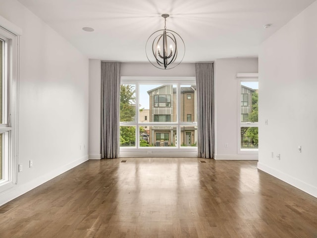unfurnished dining area featuring a chandelier, wood finished floors, and baseboards
